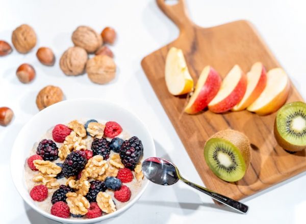 A nutritious breakfast bowl featuring fresh berries and walnuts, served with sliced fruit and kiwi.